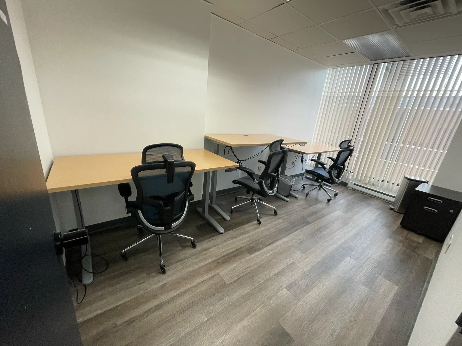 Windowed dedicated-desk office with three adjustable workstations