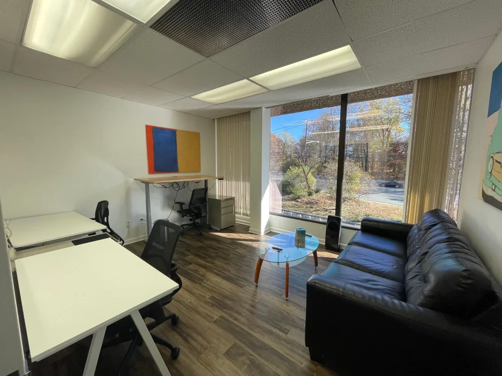 Bright furnished private office with desks, couch and large windows