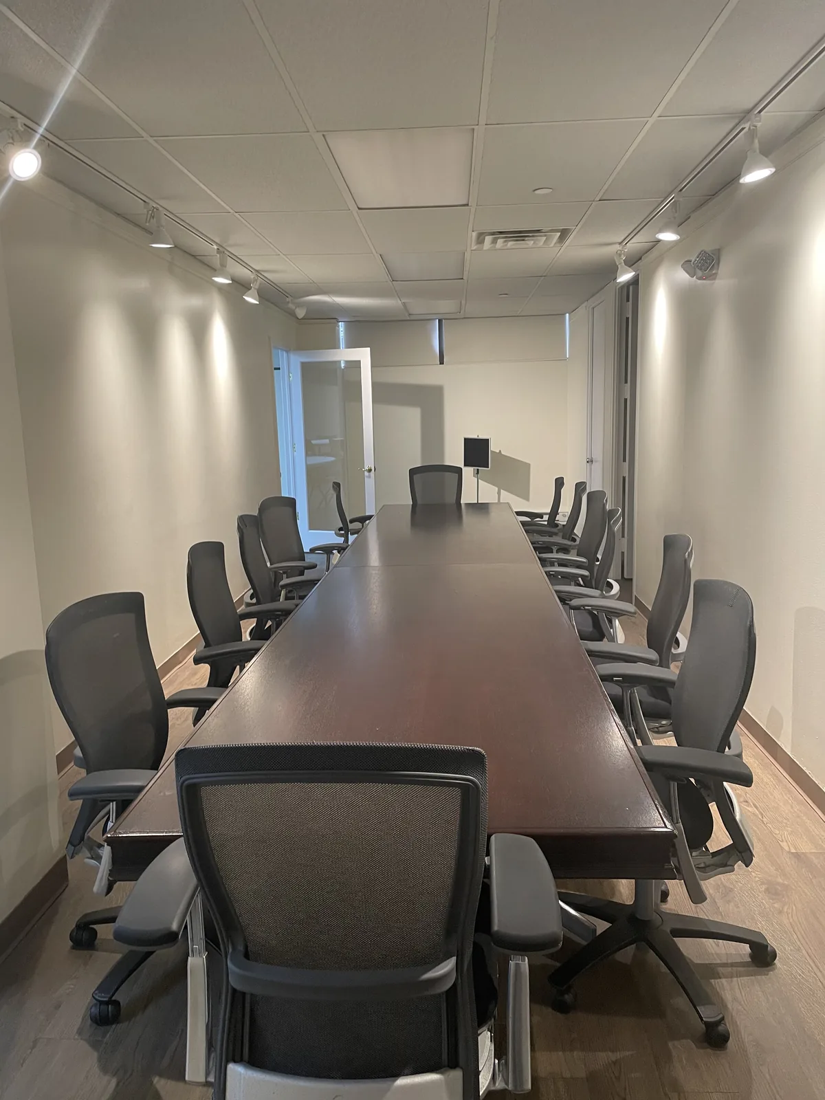 Long view of the boardroom table and seating under ceiling track lights