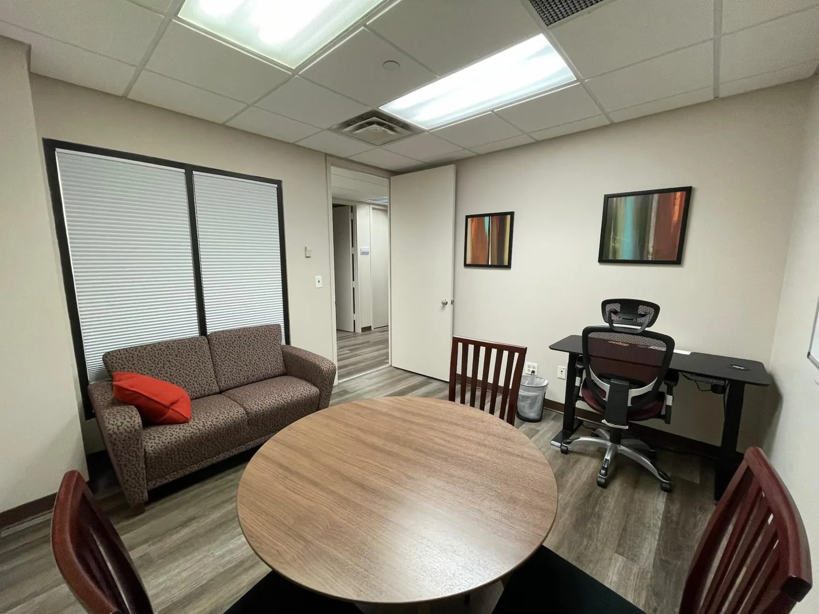 Flexible office with round meeting table, desk and seating area