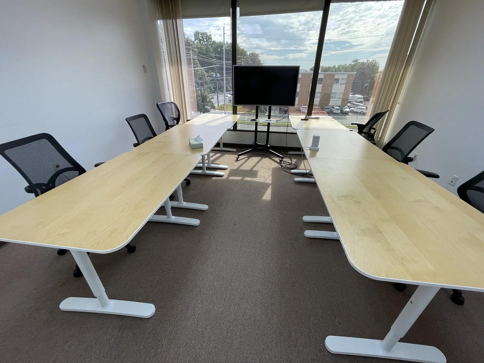 Daylit larger conference room with flexible tables, presentation monitor and window views