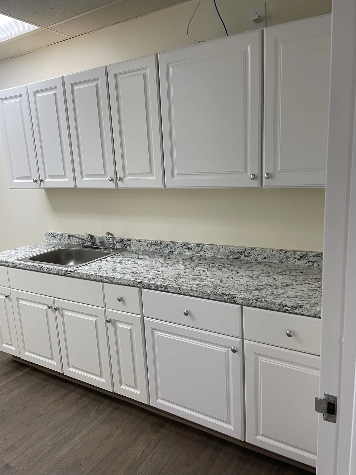 Private kitchenette with cabinets, granite counter and sink near the meeting rooms