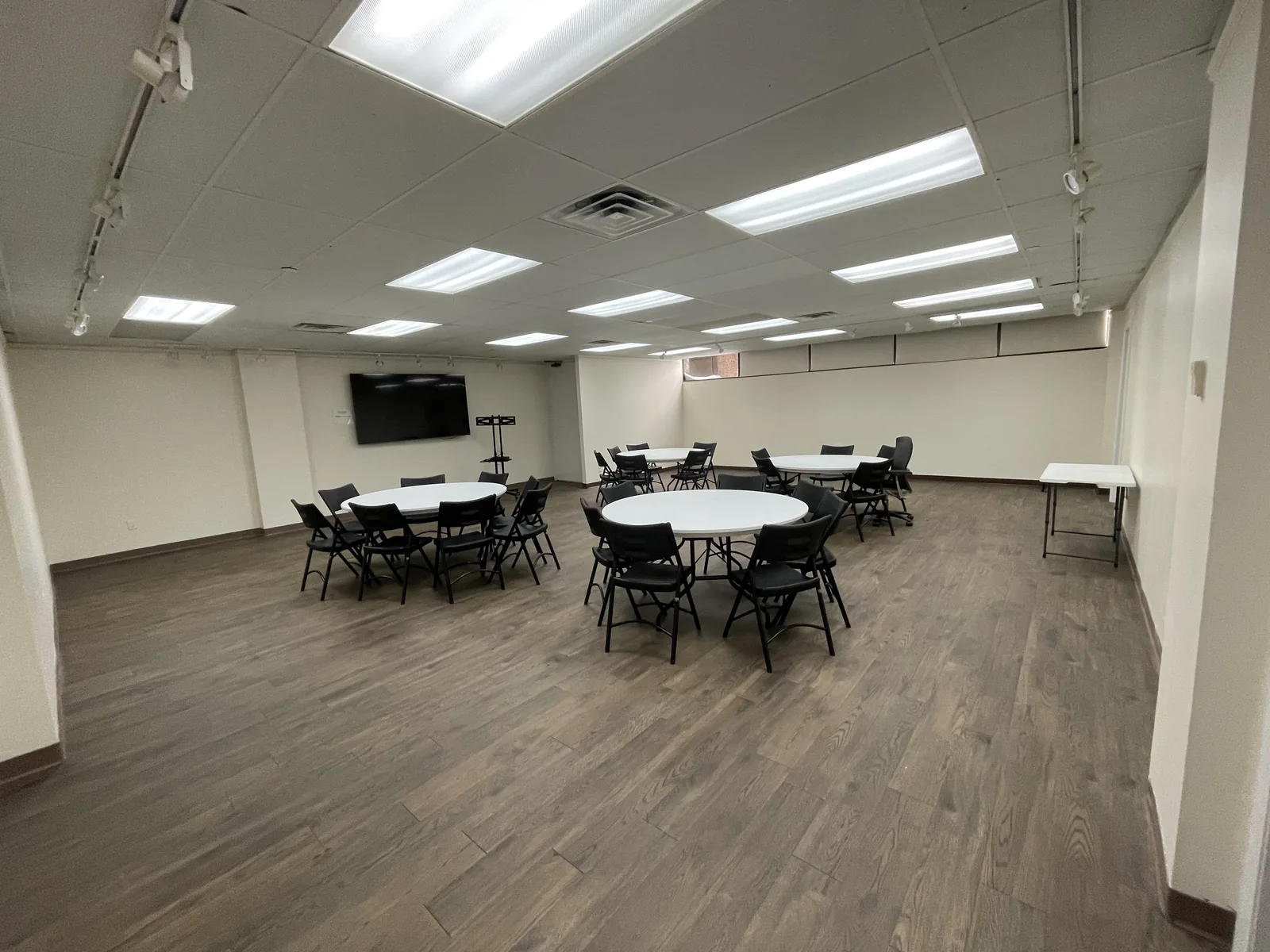 Open meeting and event area arranged with round tables and a presentation screen