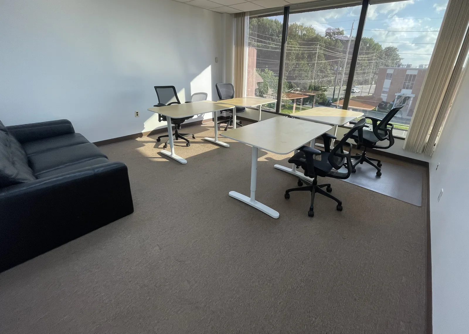 Bright windowed team office with four desks and lounge seating